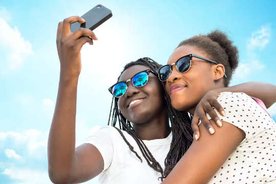 two women with arms around each other taking a selfie